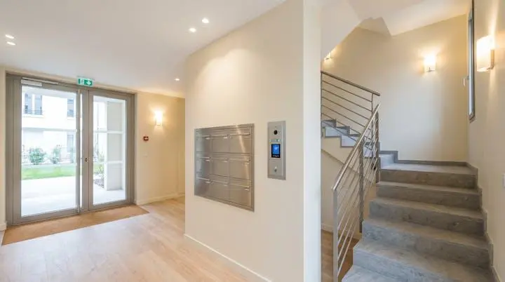 Hall d'entrée moderne d'immeuble résidentiel français avec boîtes aux lettres et escalier bien entretenus
